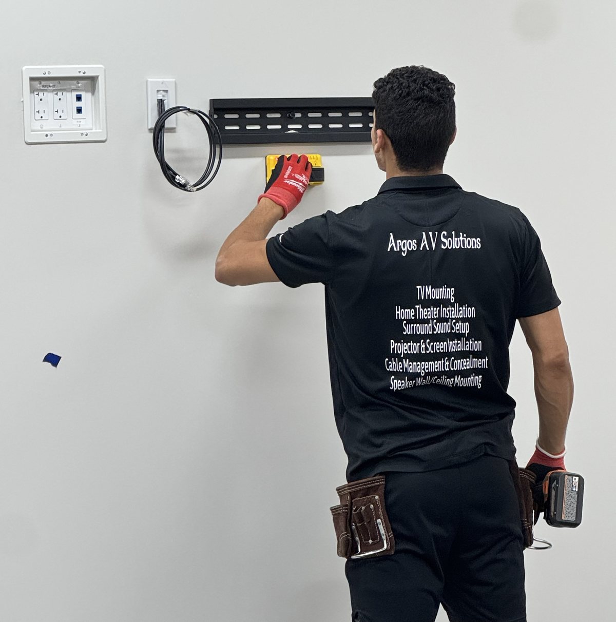 Ayoub Bey of Argos AV Solutions leveling a TV wall mount beside a recessed power and data box