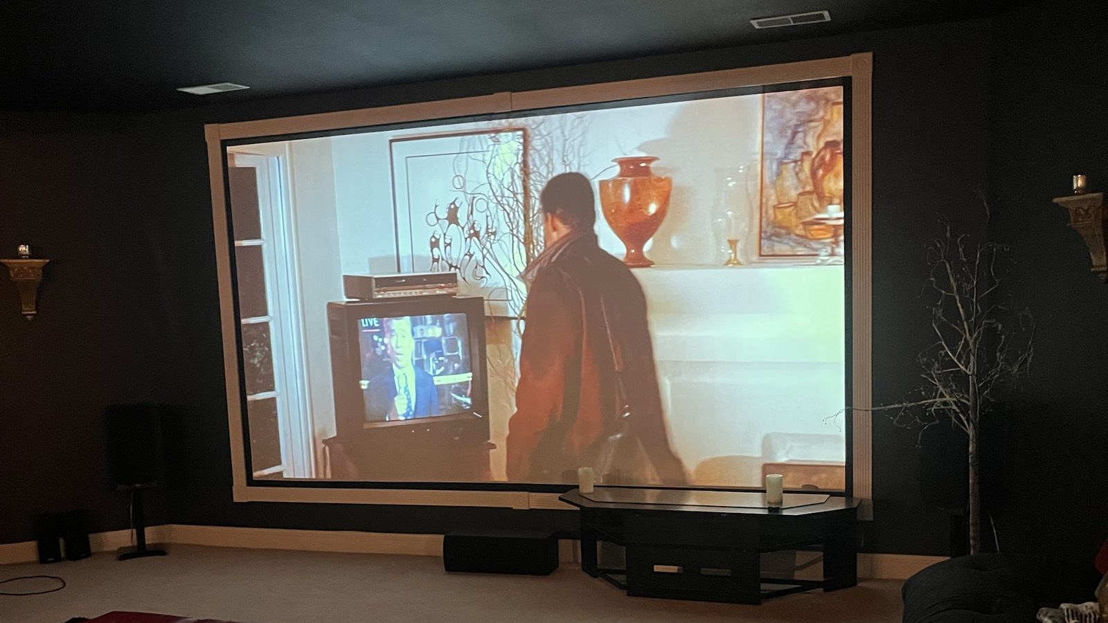 Movie night in the finished basement theater: projector screen in a dark room with floorstanding speakers, center channel and sectional seating