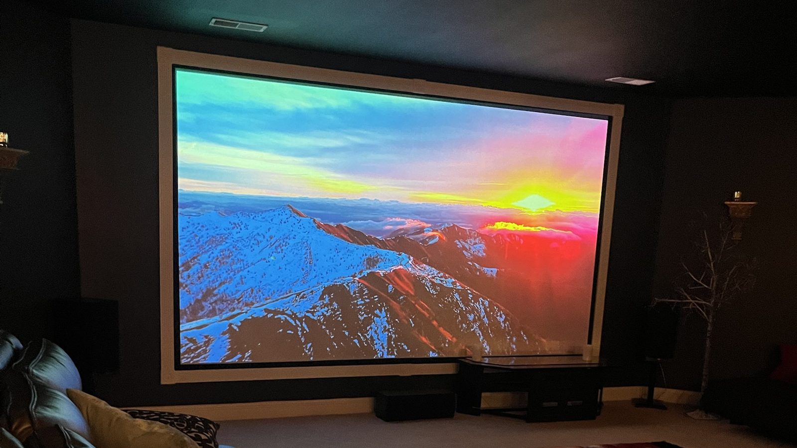 Basement home theater with a large fixed-frame projector screen and floorstanding speakers