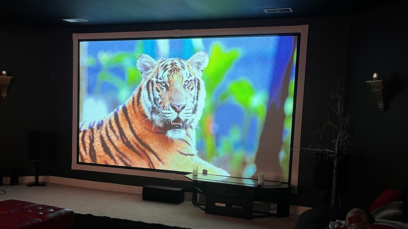 Basement home theater with a large fixed-frame projector screen and floorstanding speakers