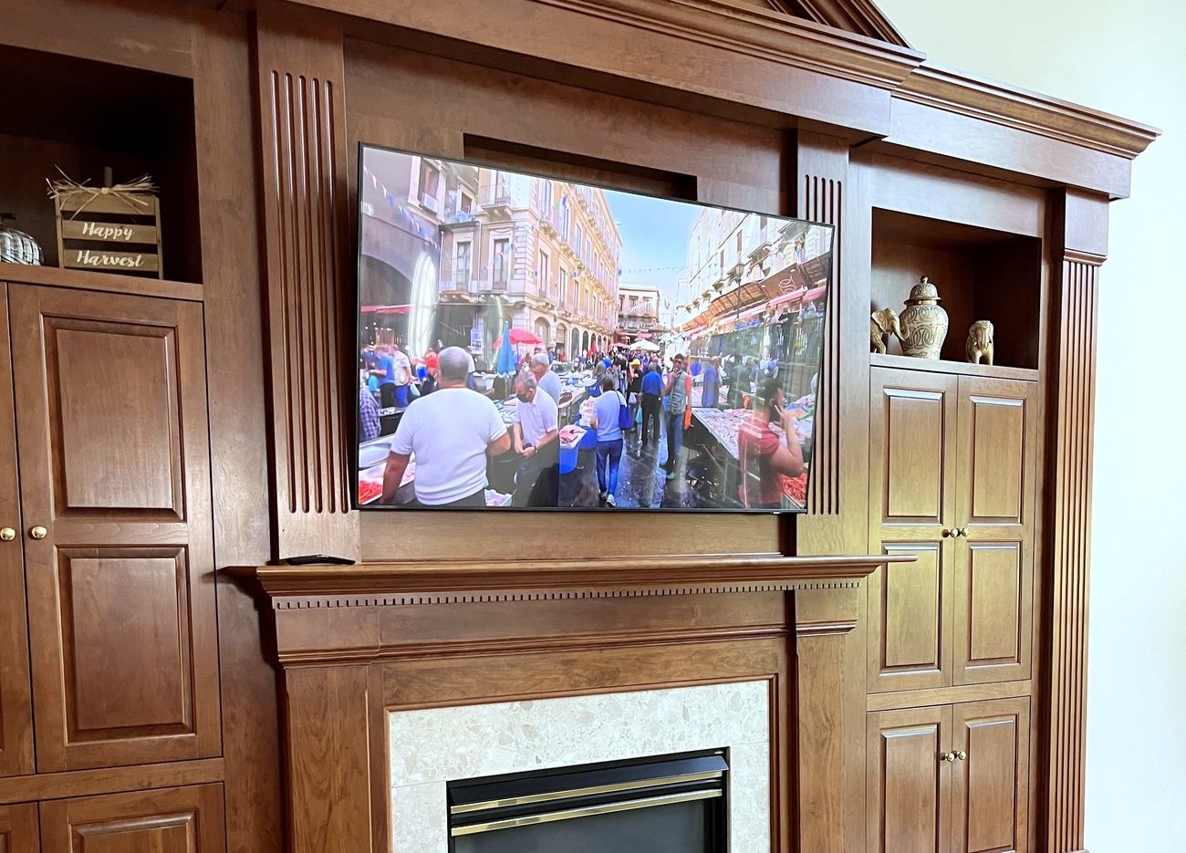 TV recessed above a fireplace in cherry built-in cabinetry, wiring concealed