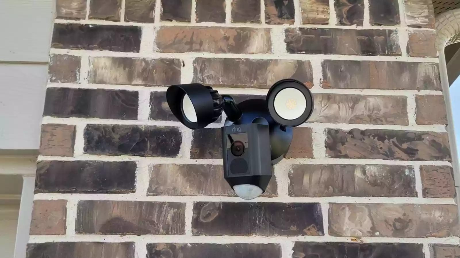 Ring floodlight camera mounted on a brick exterior wall — Argos AV security camera install