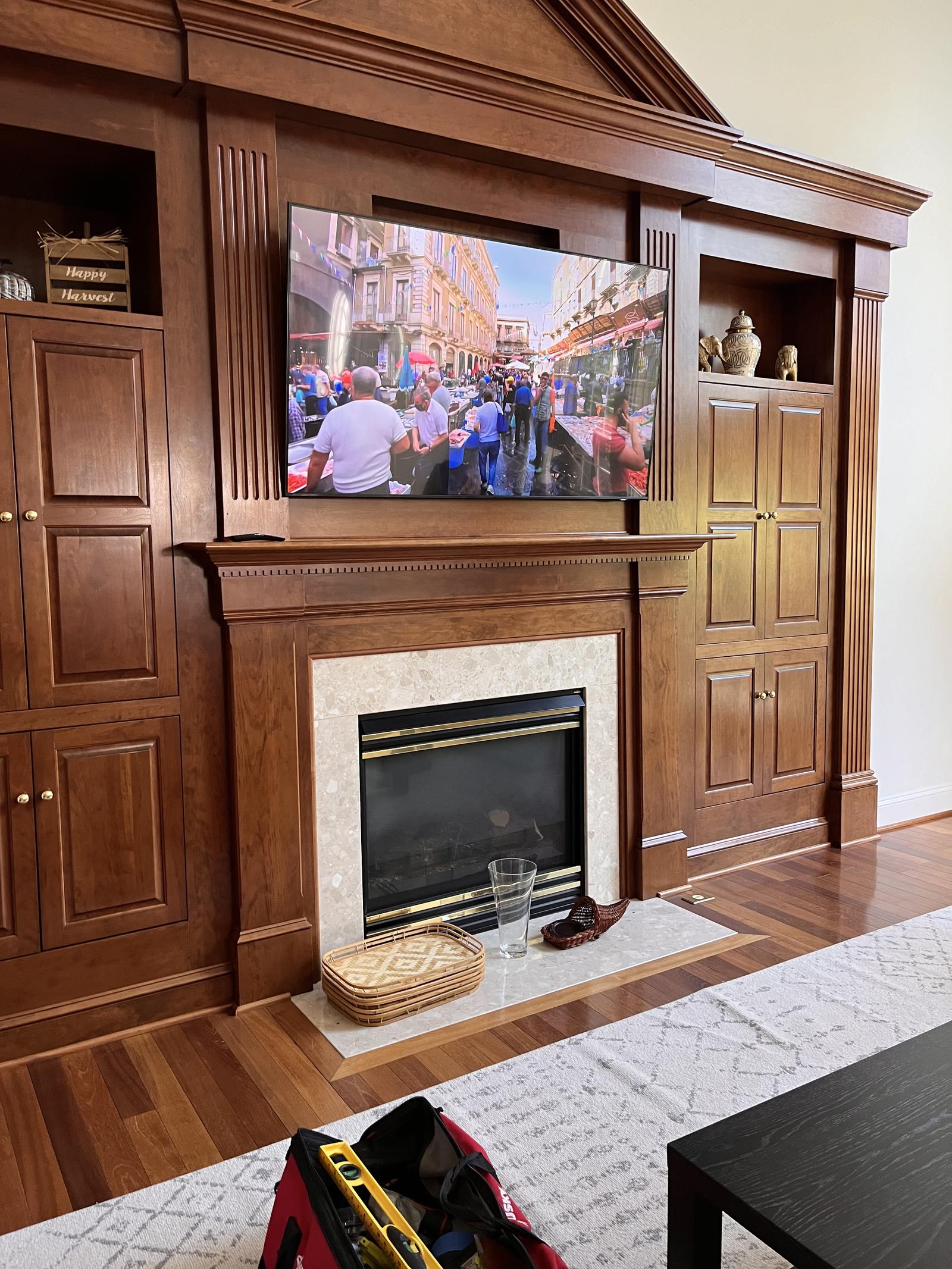 TV mounted above a fireplace in traditional wood built-in cabinetry — Argos AV installation