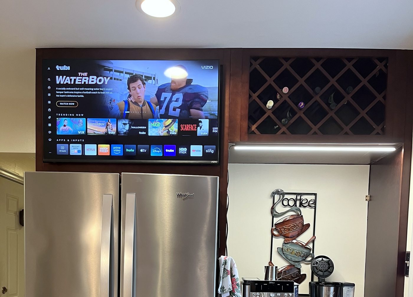 Wall-mounted TV above the fridge beside a built-in coffee and wine bar