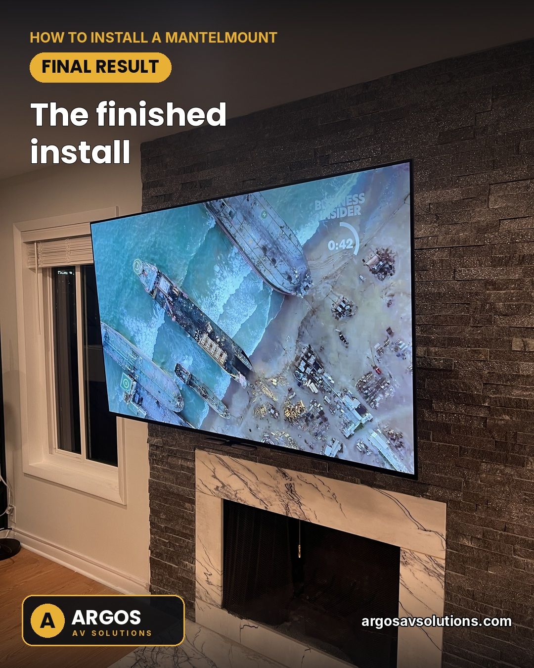 Finished MantelMount install: TV above a marble fireplace surround on a dark stacked-stone wall