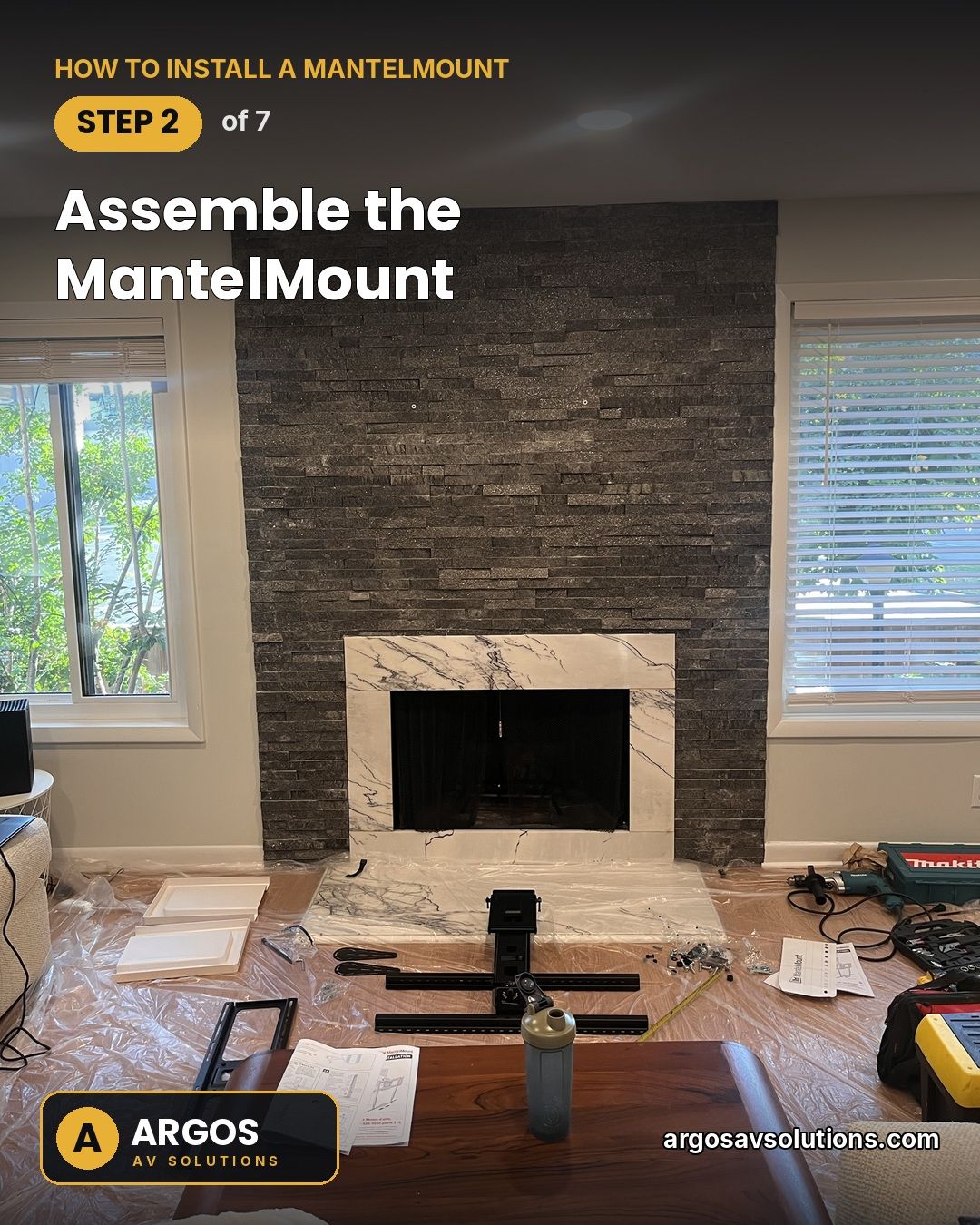 MantelMount pull-down TV mount parts assembled on the floor in front of a stacked-stone fireplace