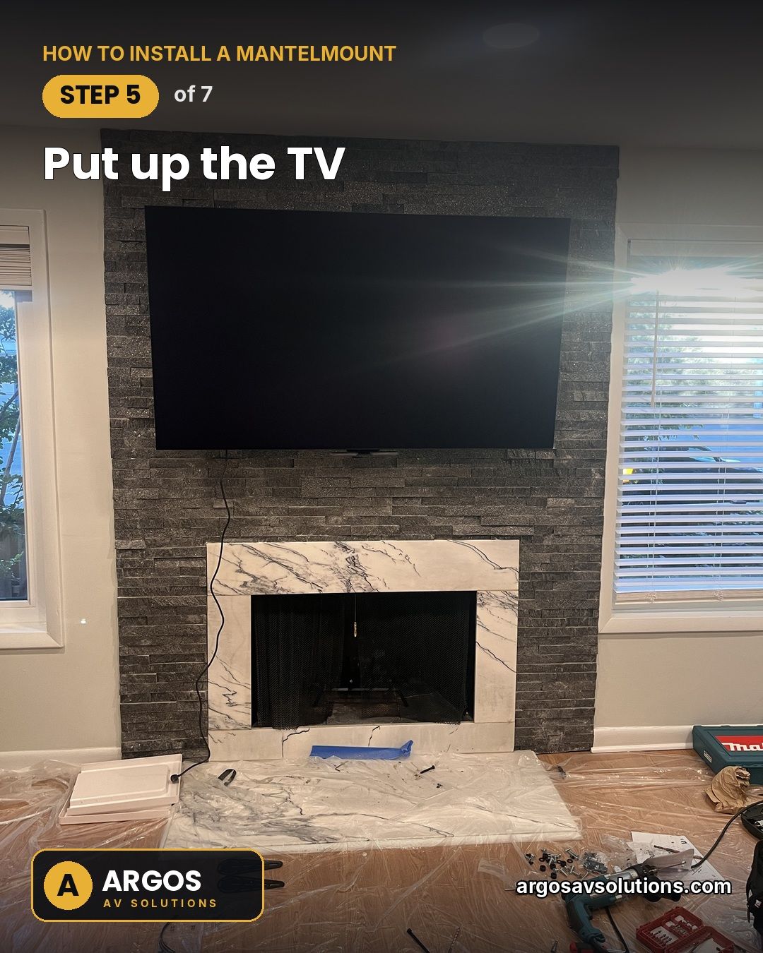 Large TV hung on a MantelMount above a stacked-stone and marble fireplace