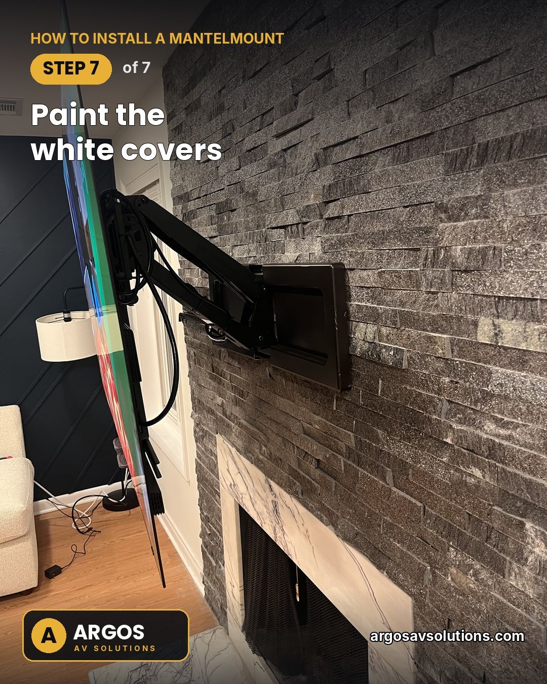 MantelMount wall-plate covers painted black to blend into a dark stacked-stone fireplace, with cables bundled along the arm