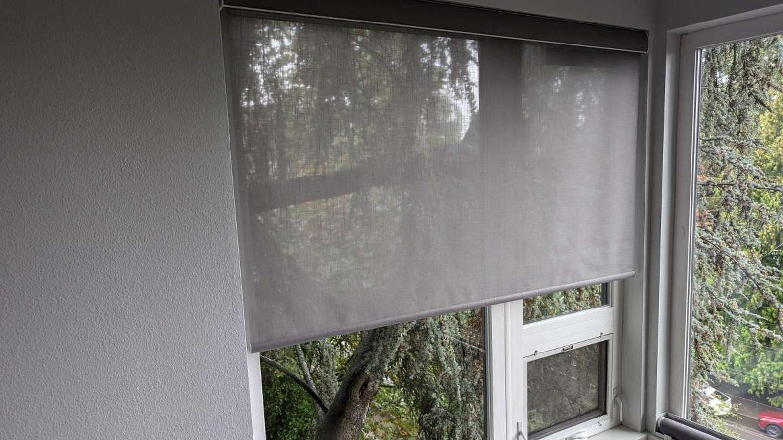 Motorized roller shade installed on a corner window — Argos AV lighting control and motorized shades