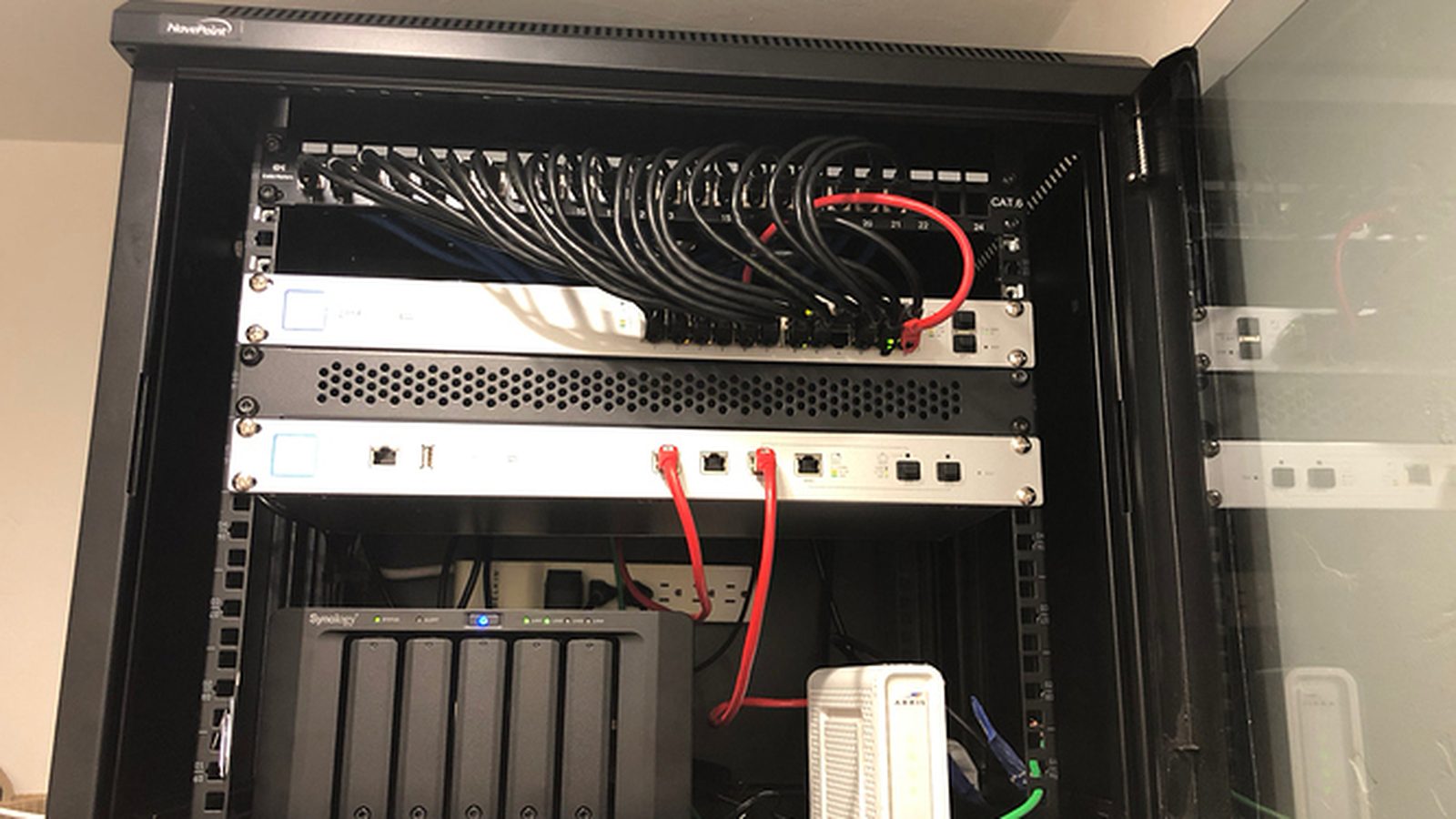 Wall-mounted network rack with Cat6 patch panel, Ubiquiti switch and gateway, and NAS — Argos AV networking and Wi-Fi install