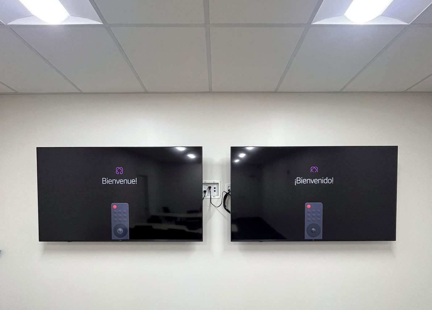 Two wall-mounted displays running welcome screens in a lobby