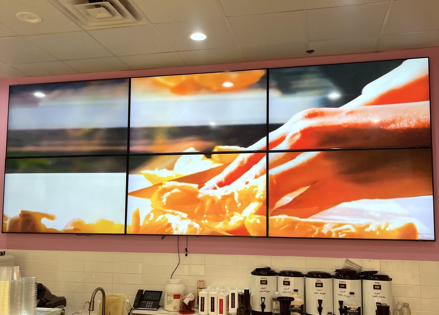 Six-panel video wall installed above a cafe service counter